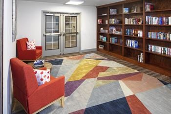 A library with red chairs and a colorful rug
